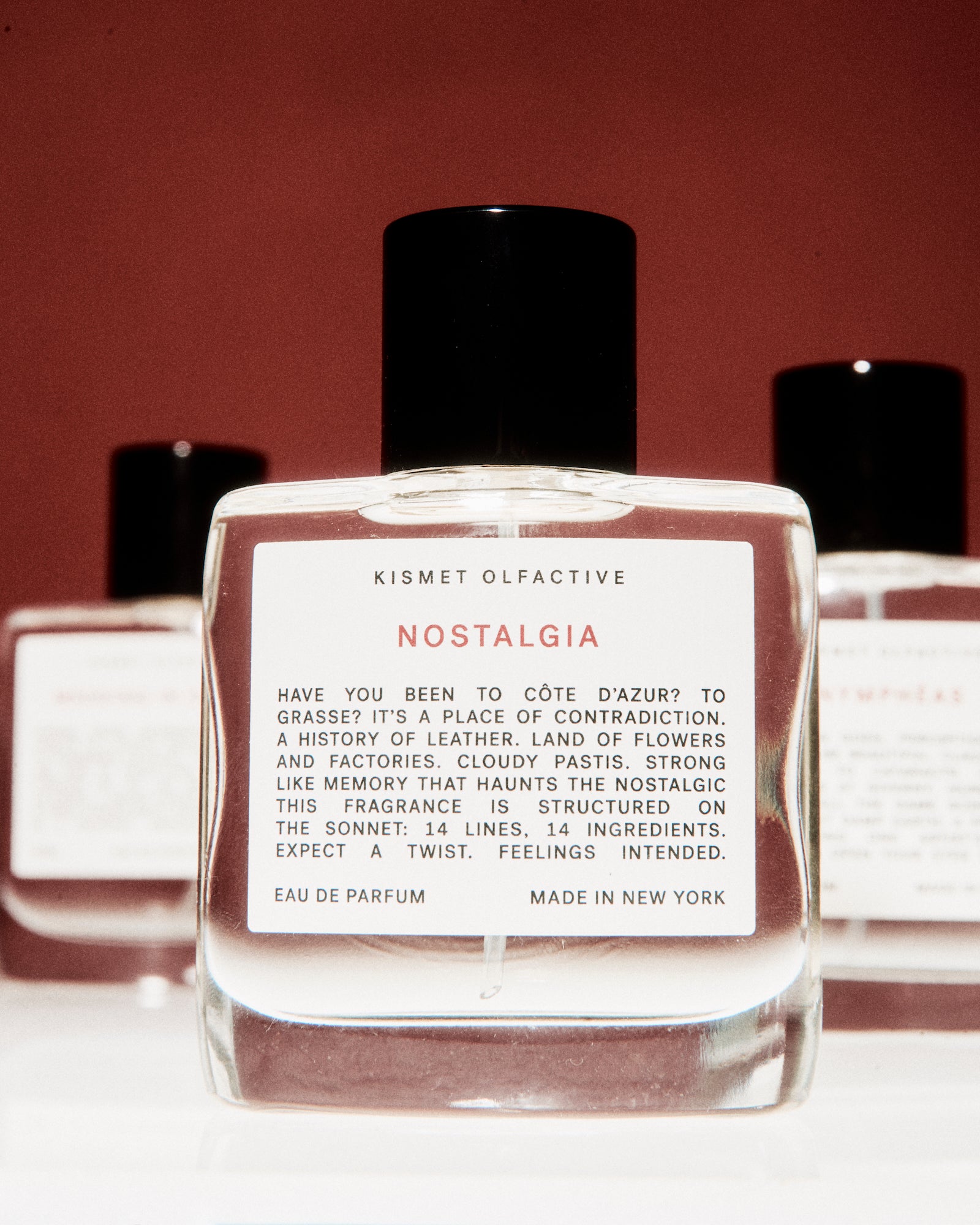Perfume bottle labeled 'Nostalgia' by Kismet Olfactive with a red background
